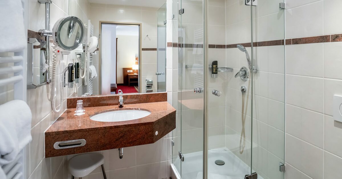 Hotel_Europaeischer_Hof_Doppel_Komfort_Innenhof_Badezimmer_1 Badezimmer mit Waschbecken, Dusche und Spiegel in einem günstigen Doppelzimmer in München