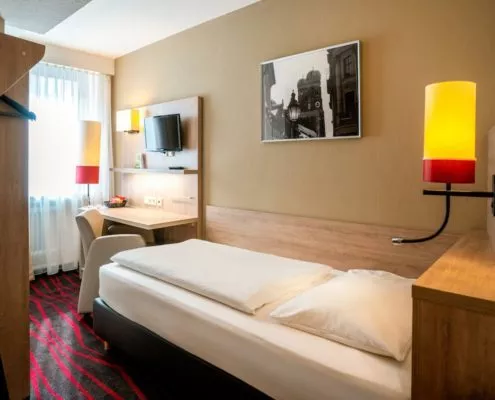 Helles und voll ausgestattetes Einzelzimmer mit Bett, Schreibtisch, Stuhl und Fernseher in einem günstigen und zentralen Hotel am Hauptbahnhof in München