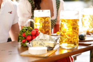 Zwei Bier, eine Käseplatte und Radieschen auf einem Holztisch in einem Biergarten in München