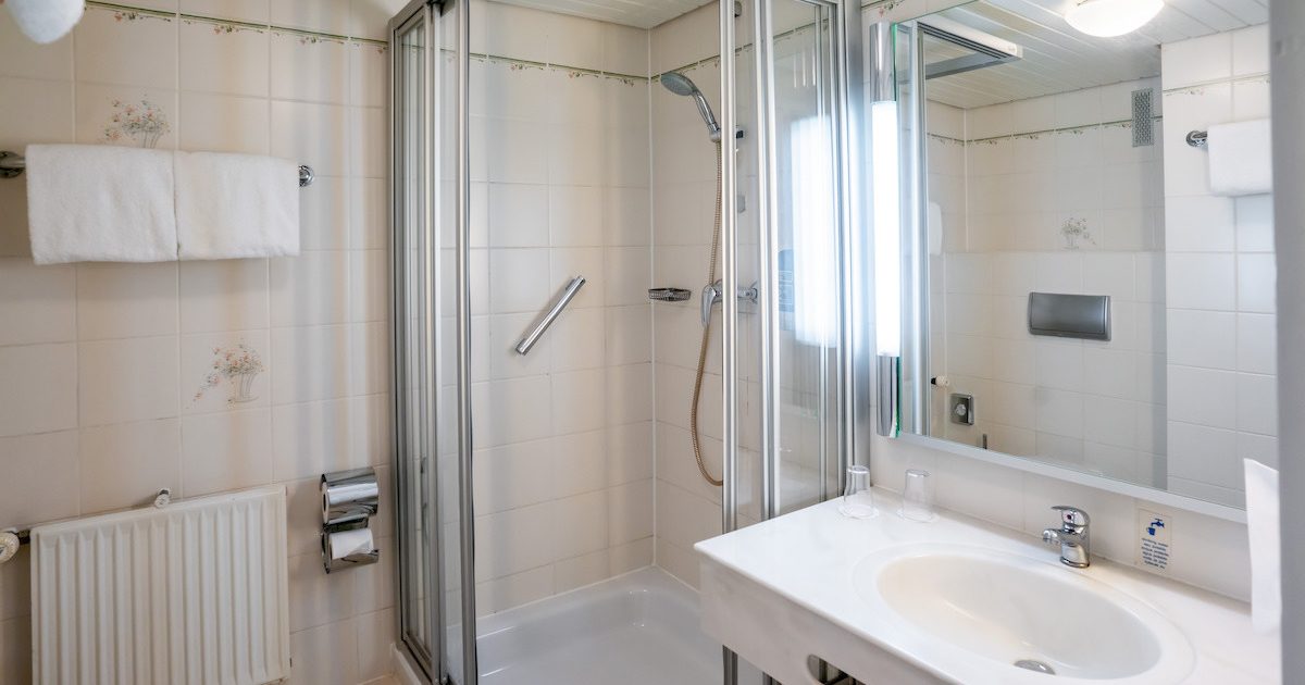 Hotel_Europaeischer_Hof_Doppel_Urban_Smart_Badezimmer3 Badezimmer mit Dusche, Handtuchstange und einem Waschbecken mit Spiegel in einem günstigen Doppelzimmer in München