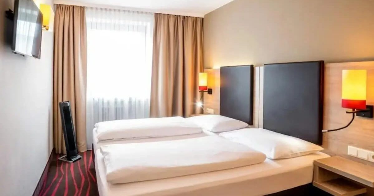 Dreibettzimmer-Doppelstandard-1 Helles Dreibettzimmer mit moderner Möblierung und zwei Betten in einem Hotelzimmer