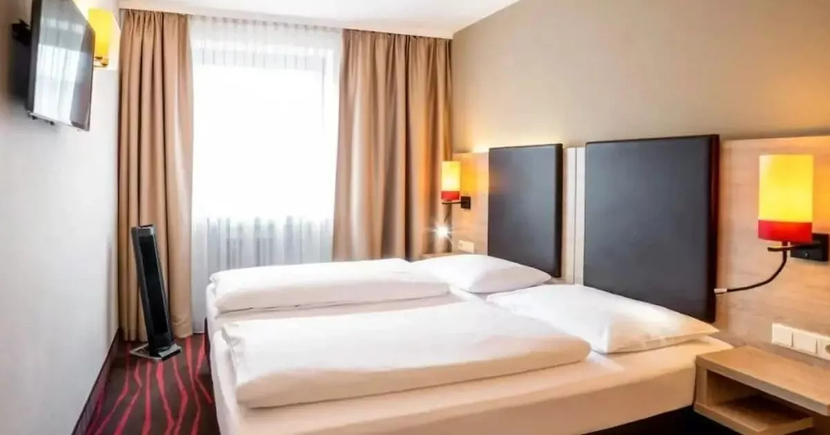 Helles Dreibettzimmer mit moderner Möblierung und zwei Betten in einem Hotelzimmer