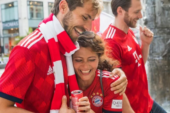 Lachende Fußballfans in den Trikots von FC Bayern München