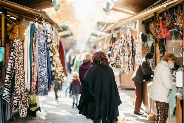 Frauen auf einem Markt mit einem Verkaufsstand mit Tüchern im Vordergrund