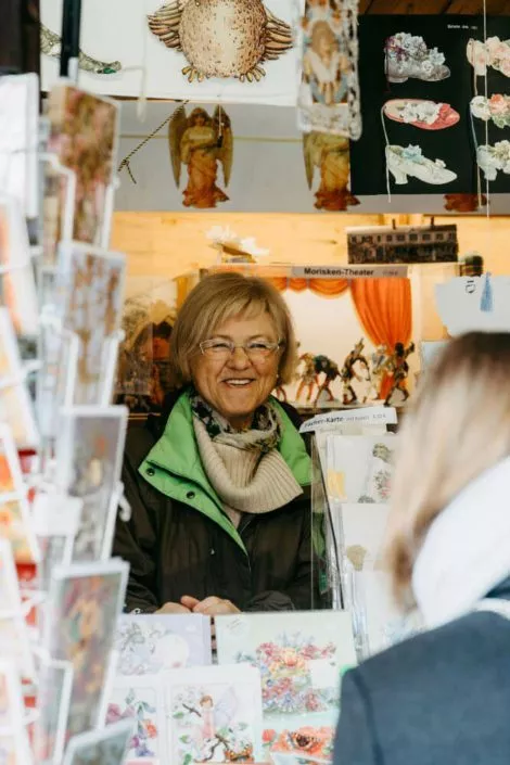 Freundliche Verkäuferin in einem Stand für Postkarten